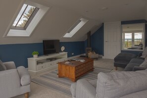 A living room with a TV, wooden coffee table, sofa, and a fireplace.