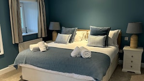 A bedroom with a large bed, two bedside tables, a window with curtains, and a ceiling light. - Owl Cote -  a cottage that sleeps 5 guests  in 3 bedrooms (Gatehouse of Fleet)