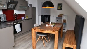 Een moderne keuken met een houten eettafel, een bankje en een hanglamp.