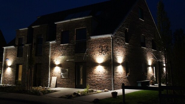 Een tweelaags bakstenen gebouw met verlichte ramen en het cijfer '33' op de gevel.