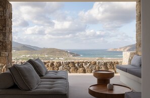 Relax in this charming outdoor seating area overlooking the coastline, featuring two sofas and a scenic view.