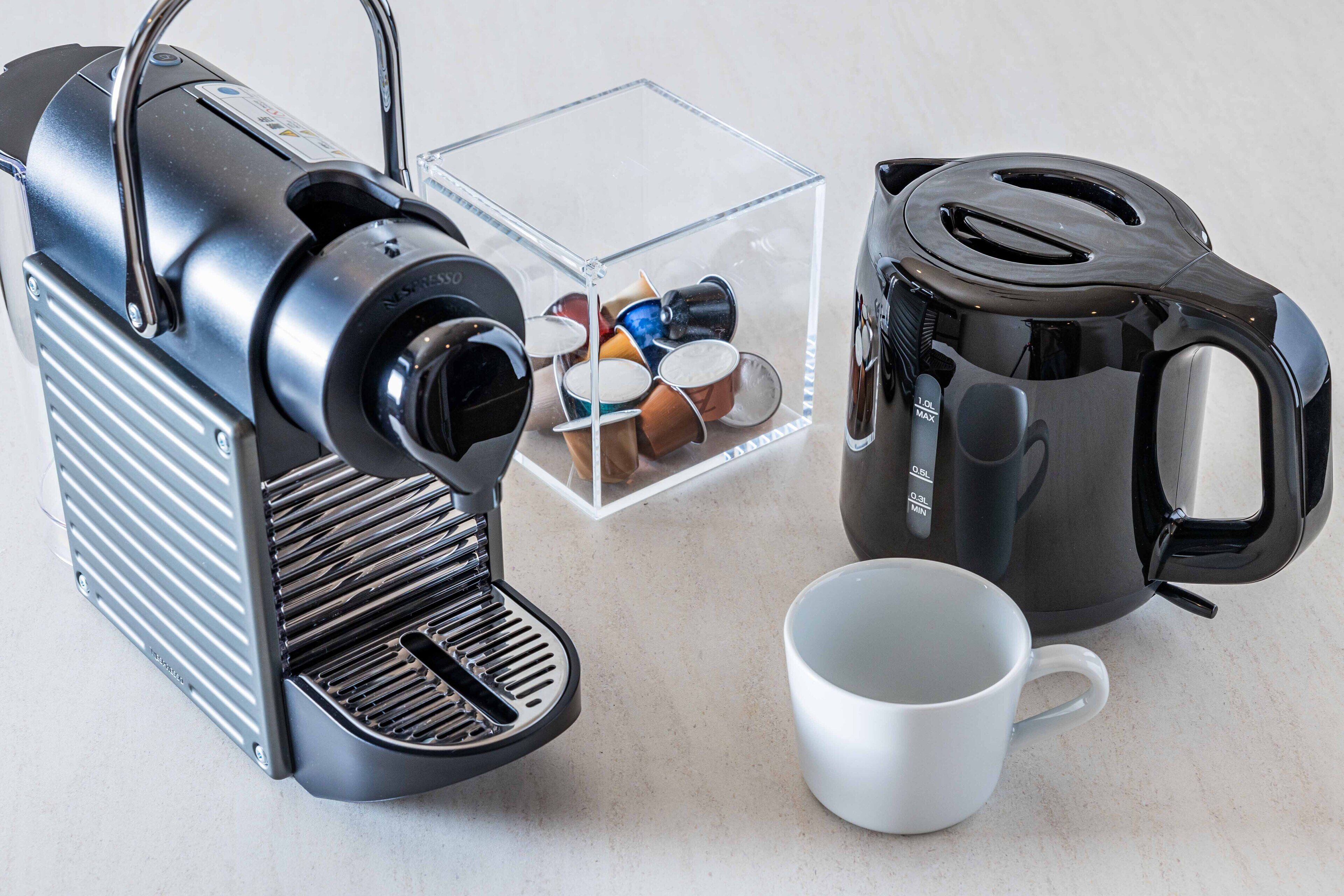 A coffee machine, a coffee pot, a cup, and a container with coffee pods.