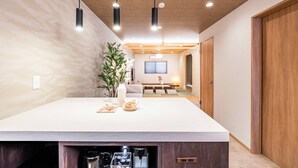 Een moderne keuken met een groot eiland, hanglampen en een uitzicht op de eetruimte.