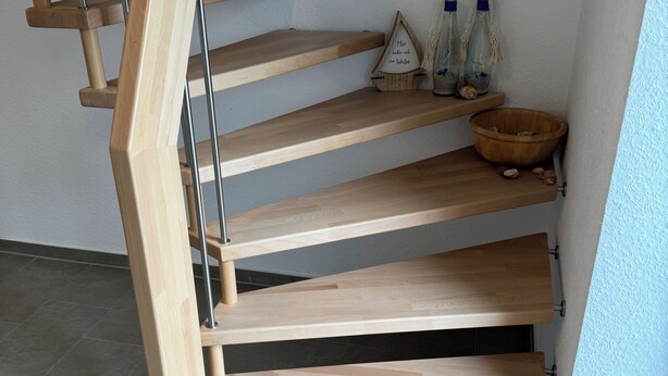 A wooden staircase with a modern design, metal handrails, and a small shelf with decorative items. - Ferienhaus in Dreschvitz für bis zu 8 Personen (Dreschvitz)