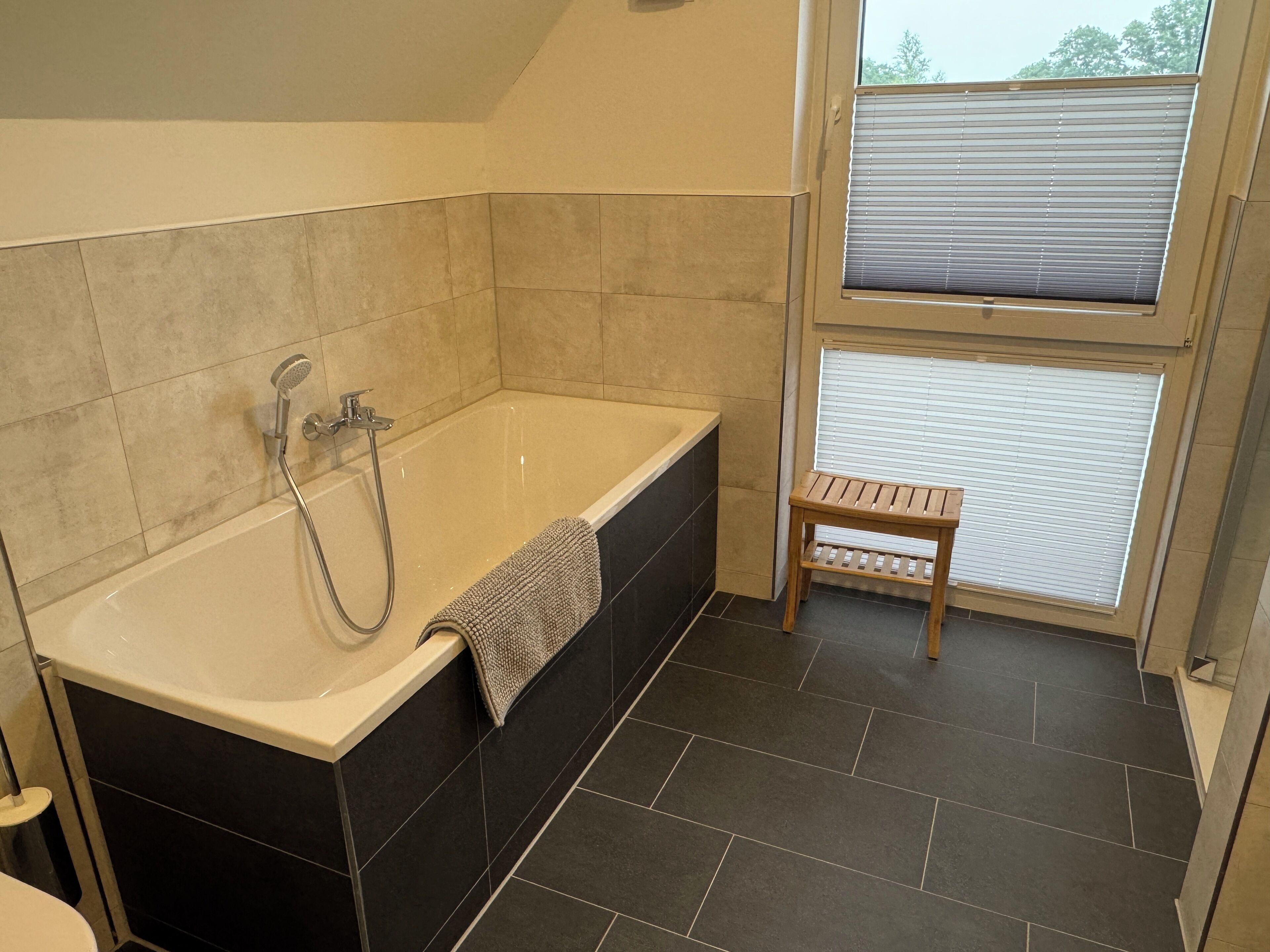 Een badkamer met een bad, een douche en een raam.
