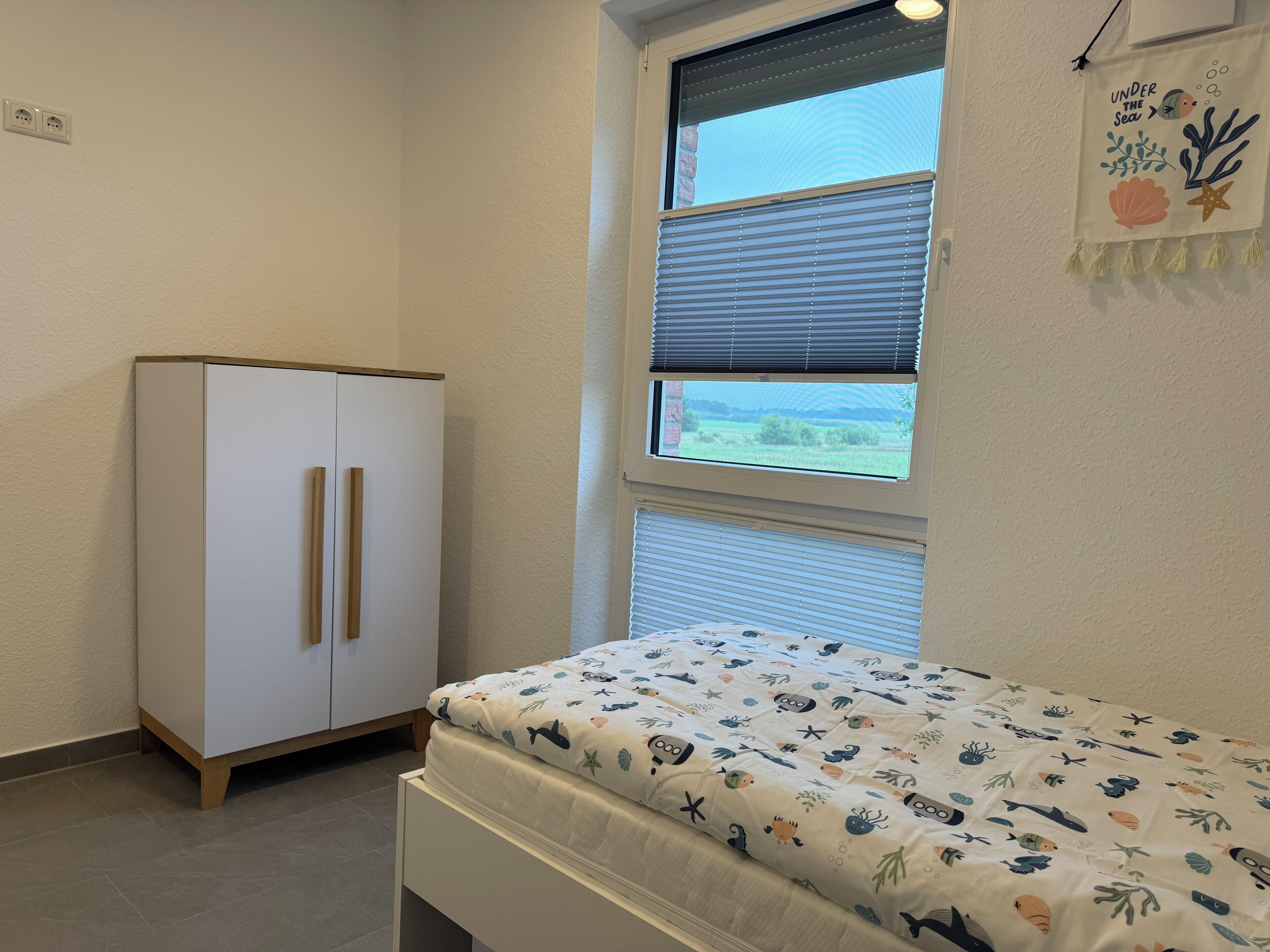 Un dormitorio con cama, armario y ventana con persianas.