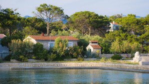 A pool with stone borders, surrounded by greenery and houses with red-tiled roofs. - Cosy Apartment Rino, only 30m from the sea, island Pag (Košljun)