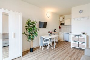 Une cuisine moderne avec des meubles blancs, un four à micro-ondes et une horloge au mur.