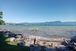 A coastal landscape with rocky shores, clear water, and distant mountains.