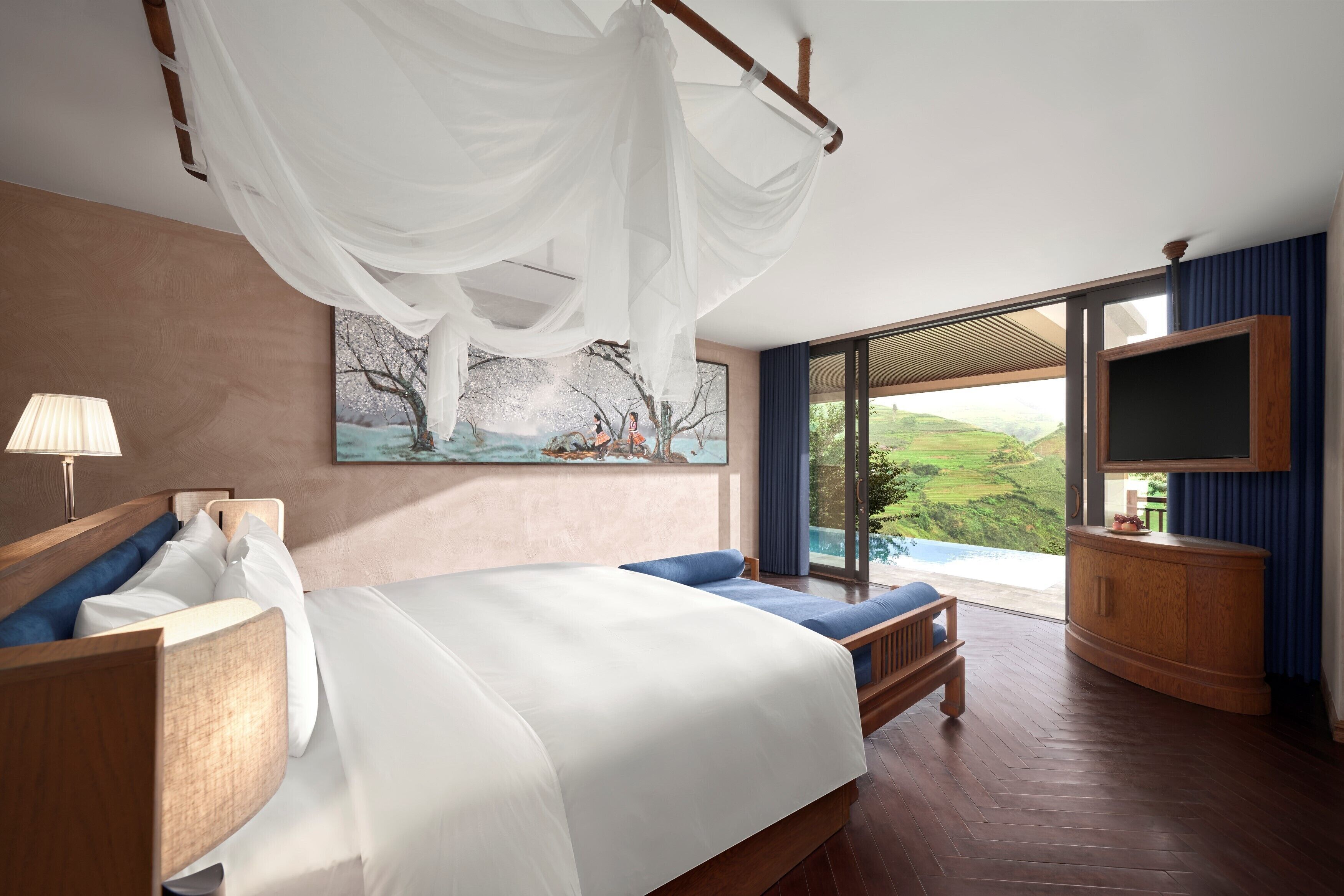 A bedroom with a large bed, a bedside table, a TV, and a window with a view of the outdoors.