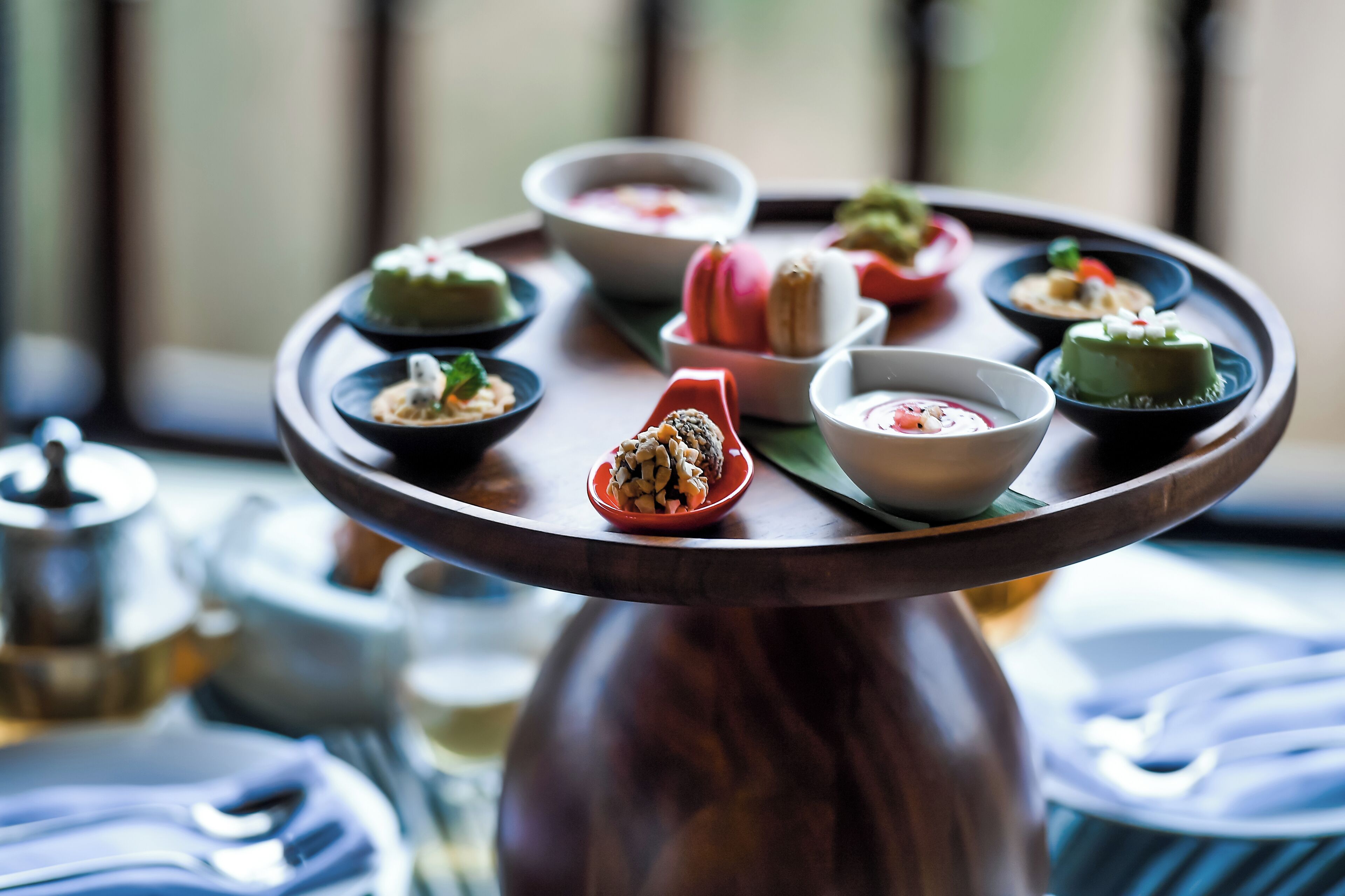 A round wooden table with various dishes and a teapot.
