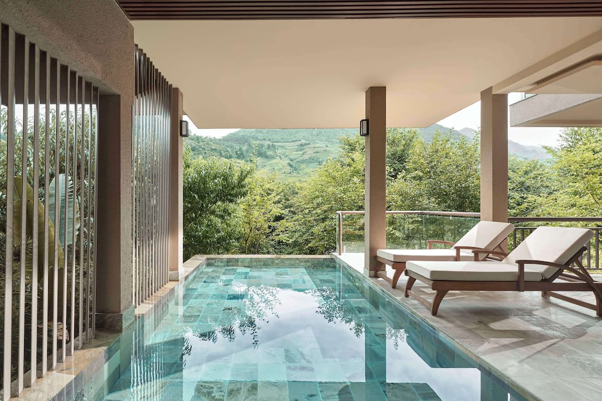 Una piscina con una vista despejada del paisaje circundante, incluyendo árboles y montañas.