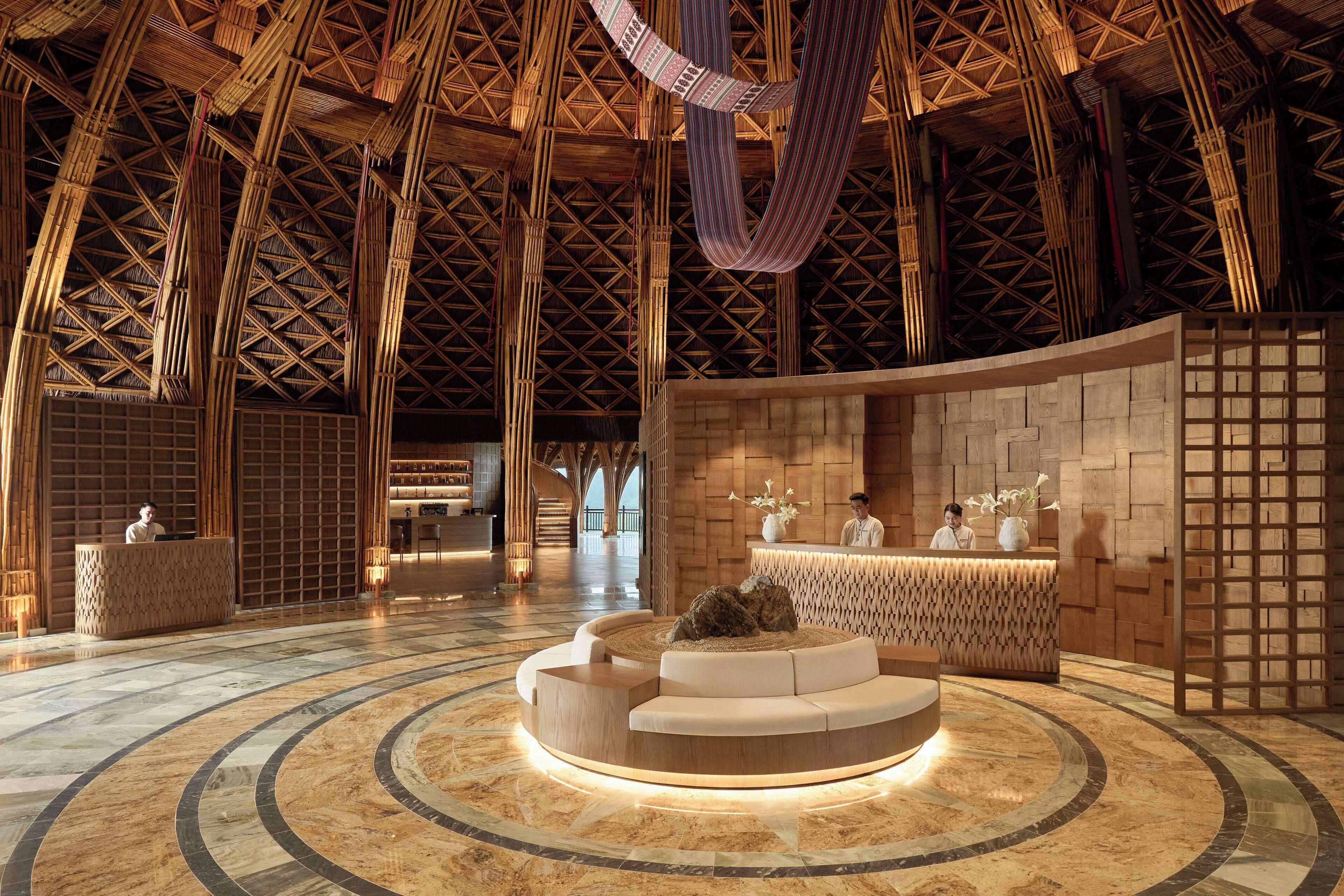 A lobby with a high, bamboo-patterned ceiling, a central seating area, and reception desks.