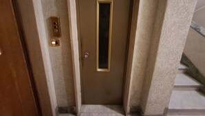 Ein schmaler Korridor mit einer Tür am Ende, einem Lichtschalter und einem kleinen Fenster.