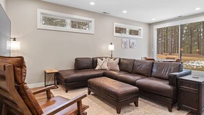 A modern living room with a sectional sofa, a wooden chair, a small side table, and a sideboard. - Camp Bluebird  in the Black Hills (Custer)