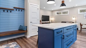 A modern kitchen with blue cabinetry, a white countertop, and pendant lighting. - Camp Bluebird  in the Black Hills (Custer)