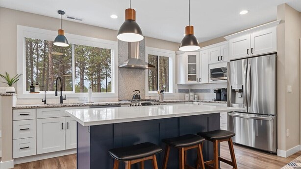 A modern kitchen with a large island, stainless steel appliances, and pendant lighting. - Camp Bluebird  in the Black Hills (Custer)