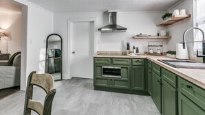Une cuisine moderne avec des meubles de couleur verte, une hotte en acier inoxydable et des plans de travail en bois.