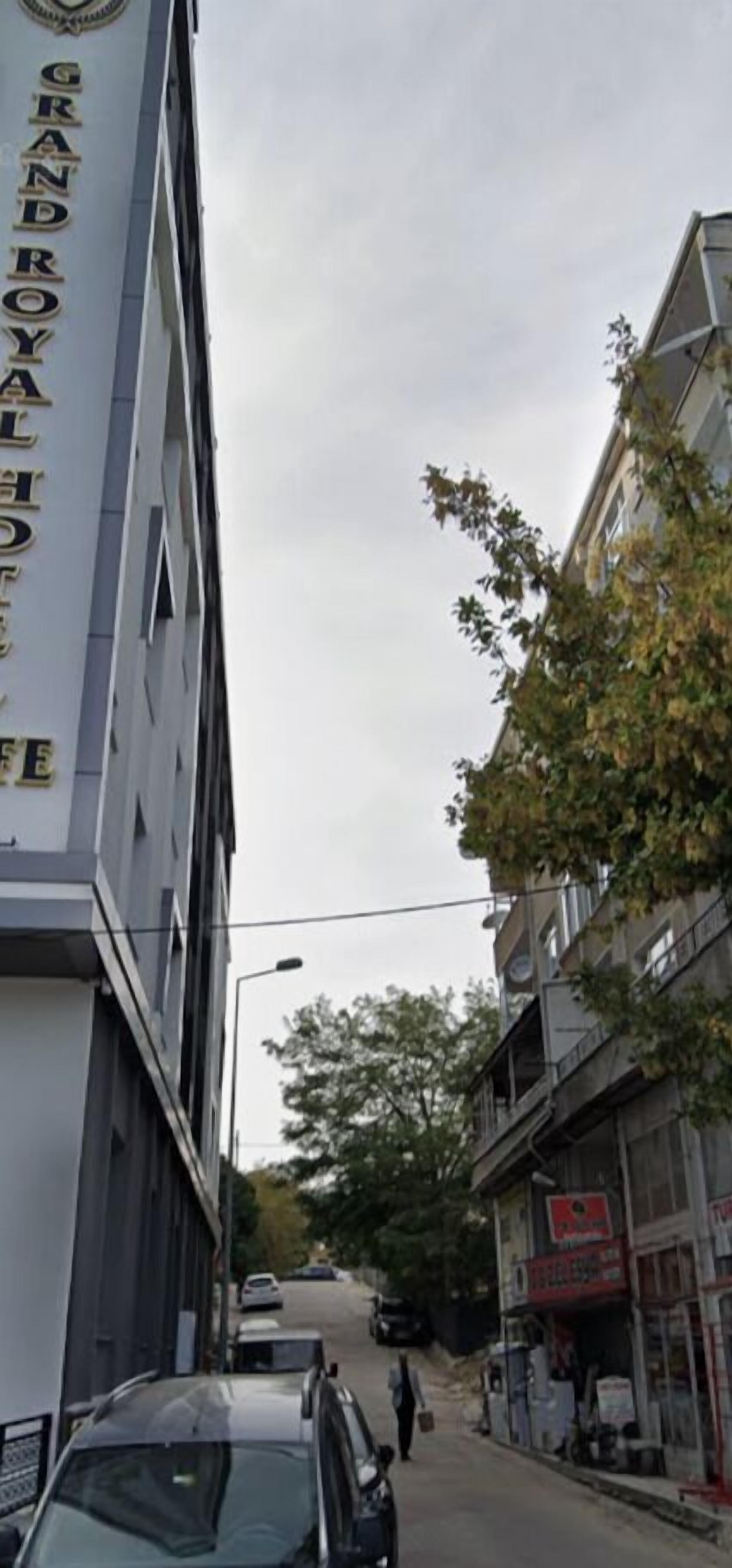 Katunäkymä, jossa vasemmalla puolella on rakennus, jonka kyltissä lukee ”GRAND ROYALE HOTEL”. Kadulla on parkkeerattuja autoja ja joku kävelee jalkakäytävällä.
