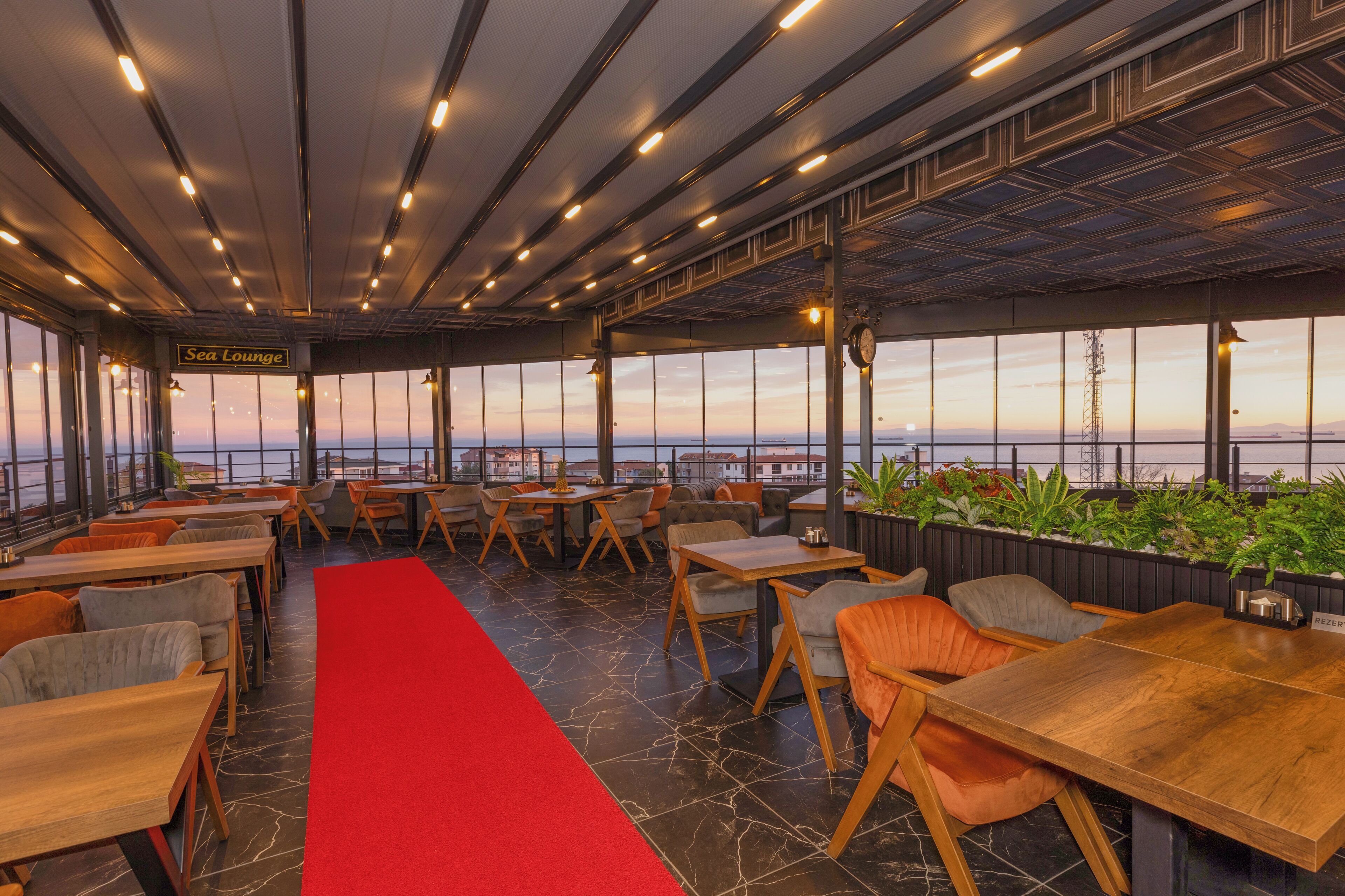Un restaurant doté d’un tapis rouge, de tables et de chaises en bois, offrant une vue panoramique.