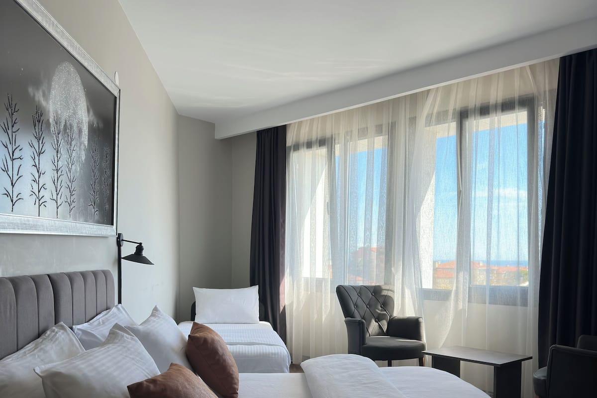 A hotel room with a large bed, a desk, a chair, and a view of the outdoors.