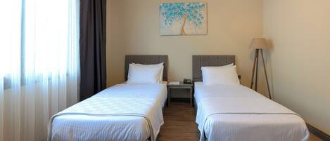 Habitación de hotel con dos camas, una mesita de noche, una lámpara y un cuadro en la pared.
