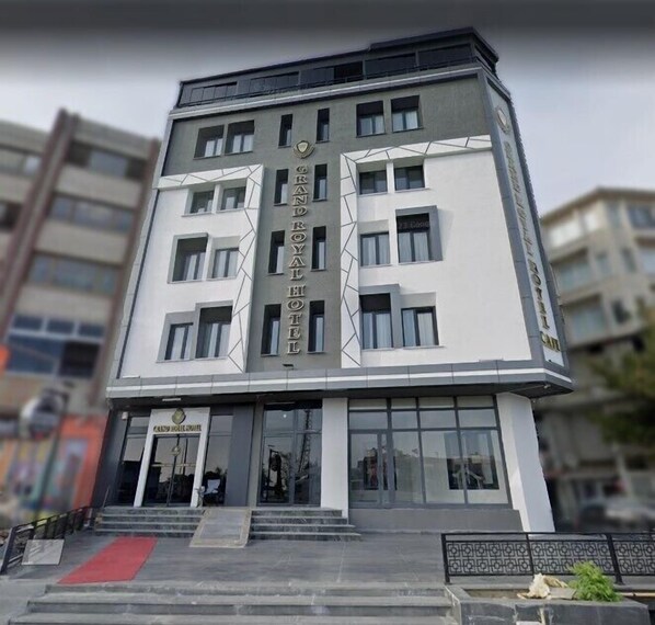 Um hotel de vários andares com fachada moderna, apresentando uma placa chamativa do Grand Royal Hotel.