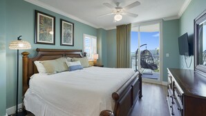 A bedroom with a large bed, a ceiling fan, a view of the city through a sliding glass door, and a TV mounted on the wall. - Waterscape A533 2Bed 2.5 Bath w Beach Service (Fort Walton Beach)
