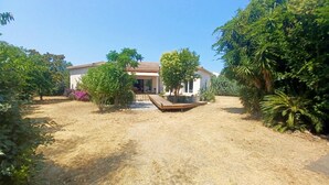 Une maison dotée d’un patio, entourée d’arbres et d’herbe sèche.