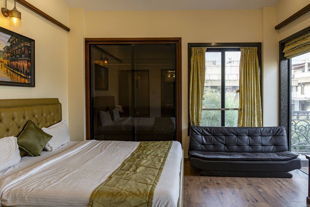 Une chambre d’hôtel avec un lit, un canapé, une porte-fenêtre coulissante et un tableau au mur.