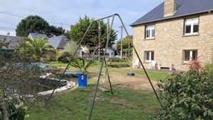A stone house with a swing set in the yard. - Appartement à 80 Mètres de la Mer, Chez L'habitant, en Rez-de-jardin (Saint-Lunaire)