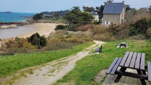 A coastal path leading to a beach with a stone house and picnic tables. - Appartement à 80 Mètres de la Mer, Chez L'habitant, en Rez-de-jardin (Saint-Lunaire)
