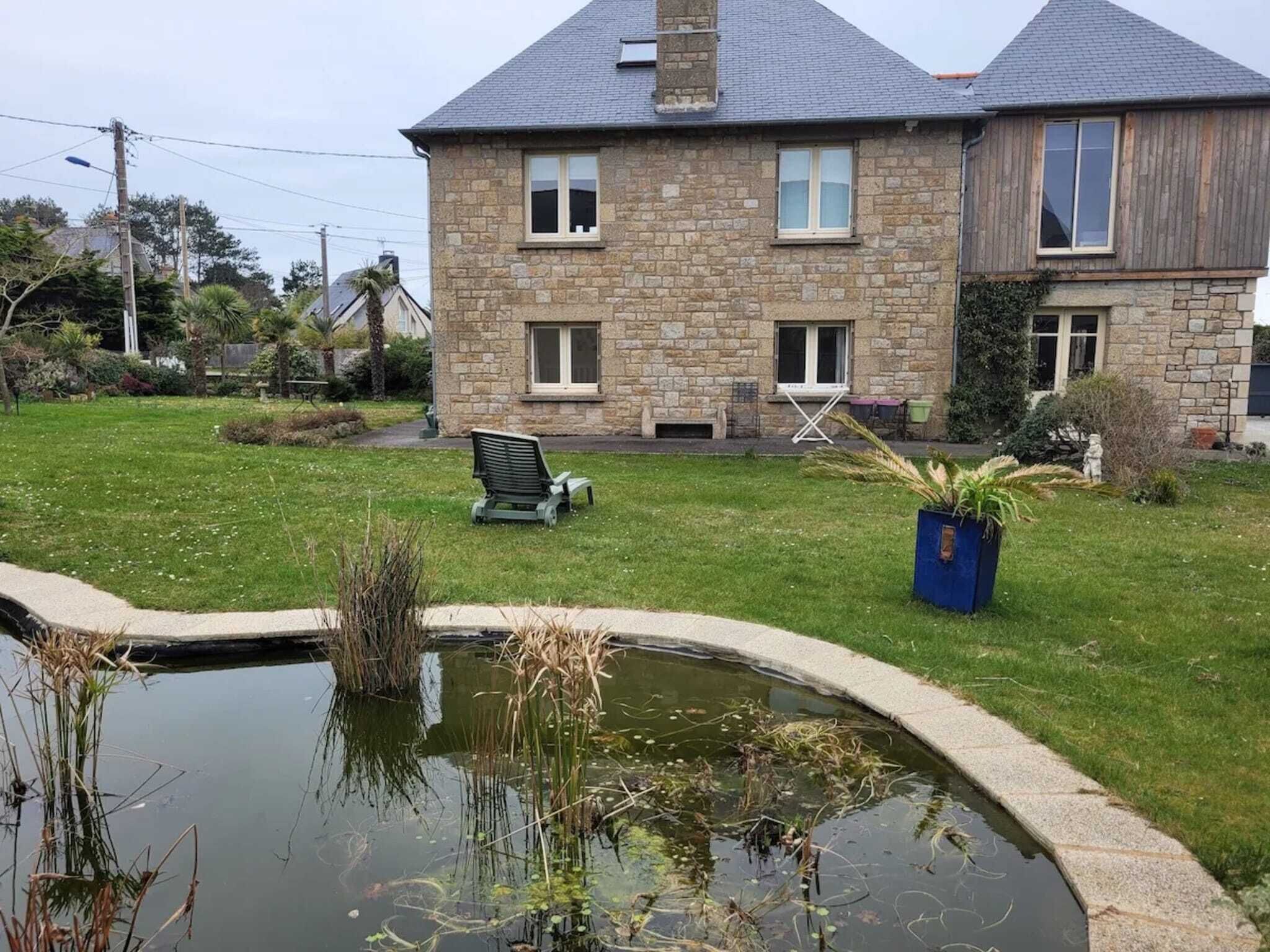 Una casa de piedra con un patio césped y un pequeño estanque.