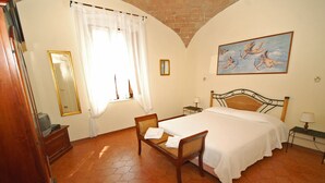 A bedroom with a bed, a chair, a nightstand, a lamp, a painting, and a mirror. - Agriturismo for 4 with a shared pool, by a village (Casole d'Elsa)
