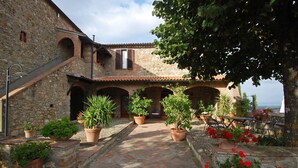 A courtyard with stone walls, potted plants, and outdoor seating. - Agriturismo for 4 with a shared pool, by a village (Casole d'Elsa)