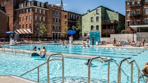 Une piscine publique dotée de plusieurs couloirs, entourée de bâtiments urbains.