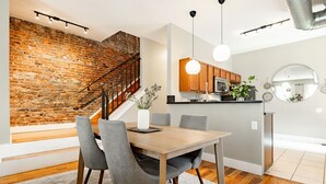 Une cuisine moderne avec des meubles en bois, un plan de travail noir et un luminaire suspendu.