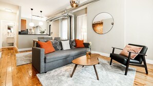 Un salon moderne avec un canapé gris, un fauteuil en cuir noir et une table basse en bois.