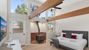 Un dormitorio moderno con una cama grande, una chimenea y ventanas amplias.