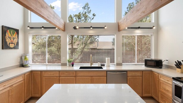 Una cocina moderna con una isla grande, armarios de madera y vistas amplias a través de ventanas grandes.