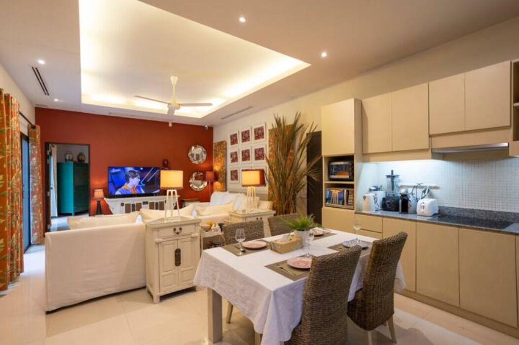 A modern living room with a sofa, TV, and dining area with a table set for two.