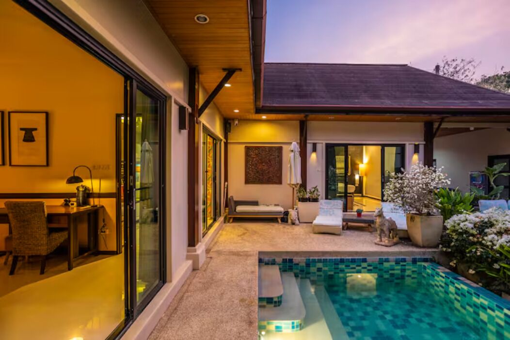 Une maison moderne dotée d’une piscine, d’un coin repas et d’un salon avec espace détente extérieur.