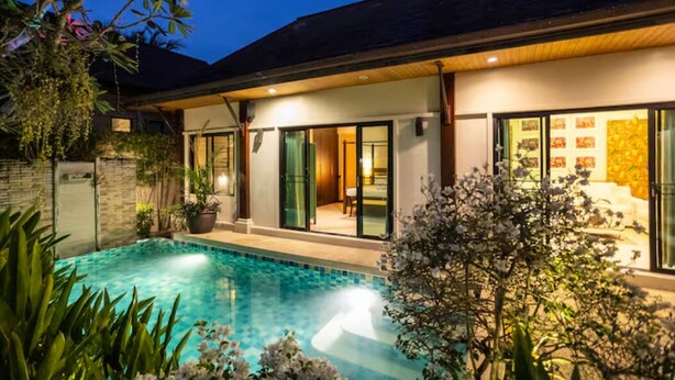 A modern house with a swimming pool, large glass doors, and a well-lit interior. - Summer Dream (Rawai)