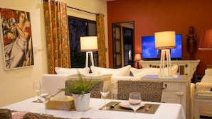 A dining area with a table set for two, a potted plant, and a painting on the wall. - Summer Dream (Rawai)