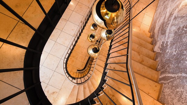 Una escalera de caracol con barandilla metálica y alfombra estampada.