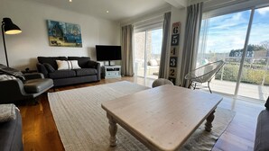 A modern living room with a sofa, a coffee table, a TV, and a balcony with a view. - North Quay (St Helens)