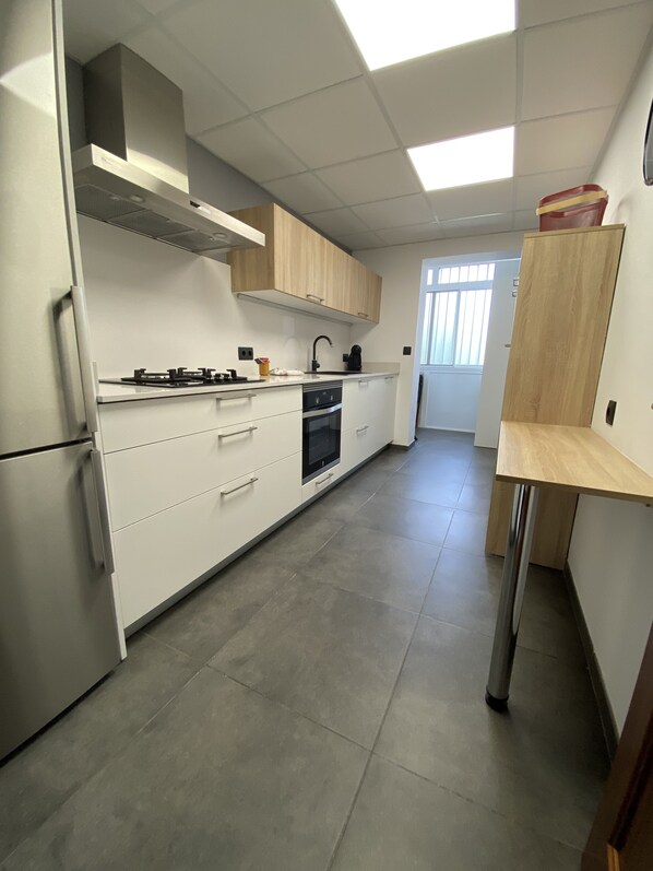 Een moderne keuken met witte kasten, een inbouwoven en een koelkast van roestvrij staal.