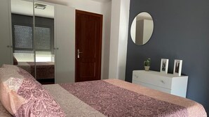 A bedroom with a bed, a dresser, a mirror, and a door.