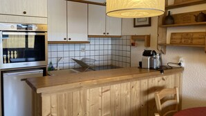 A kitchen with a wooden countertop, a built-in oven, a hanging light fixture, and a tiled backsplash.