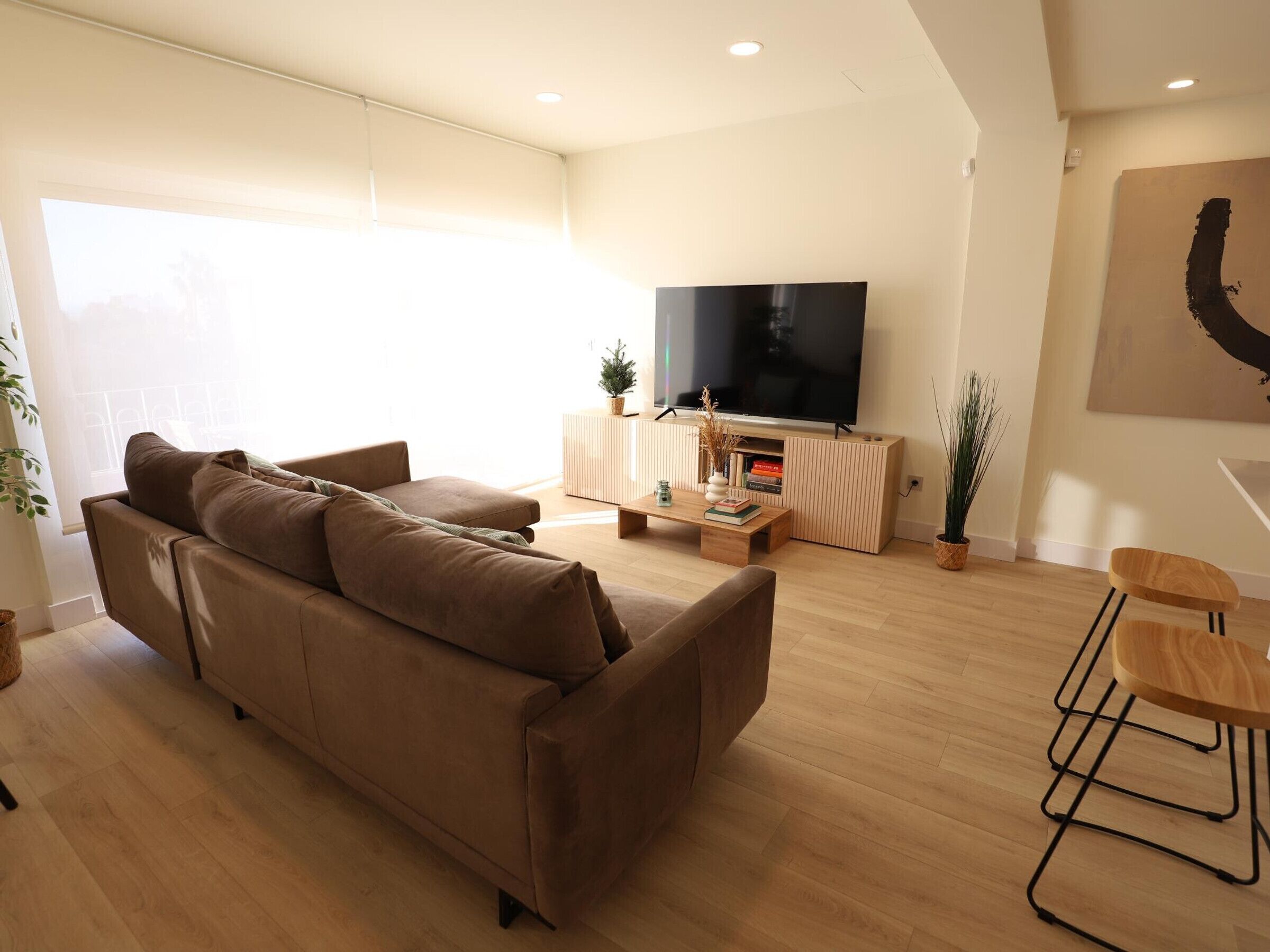 Ein modernes Wohnzimmer mit Sofa, Couchtisch, Fernseher und Essbereich.